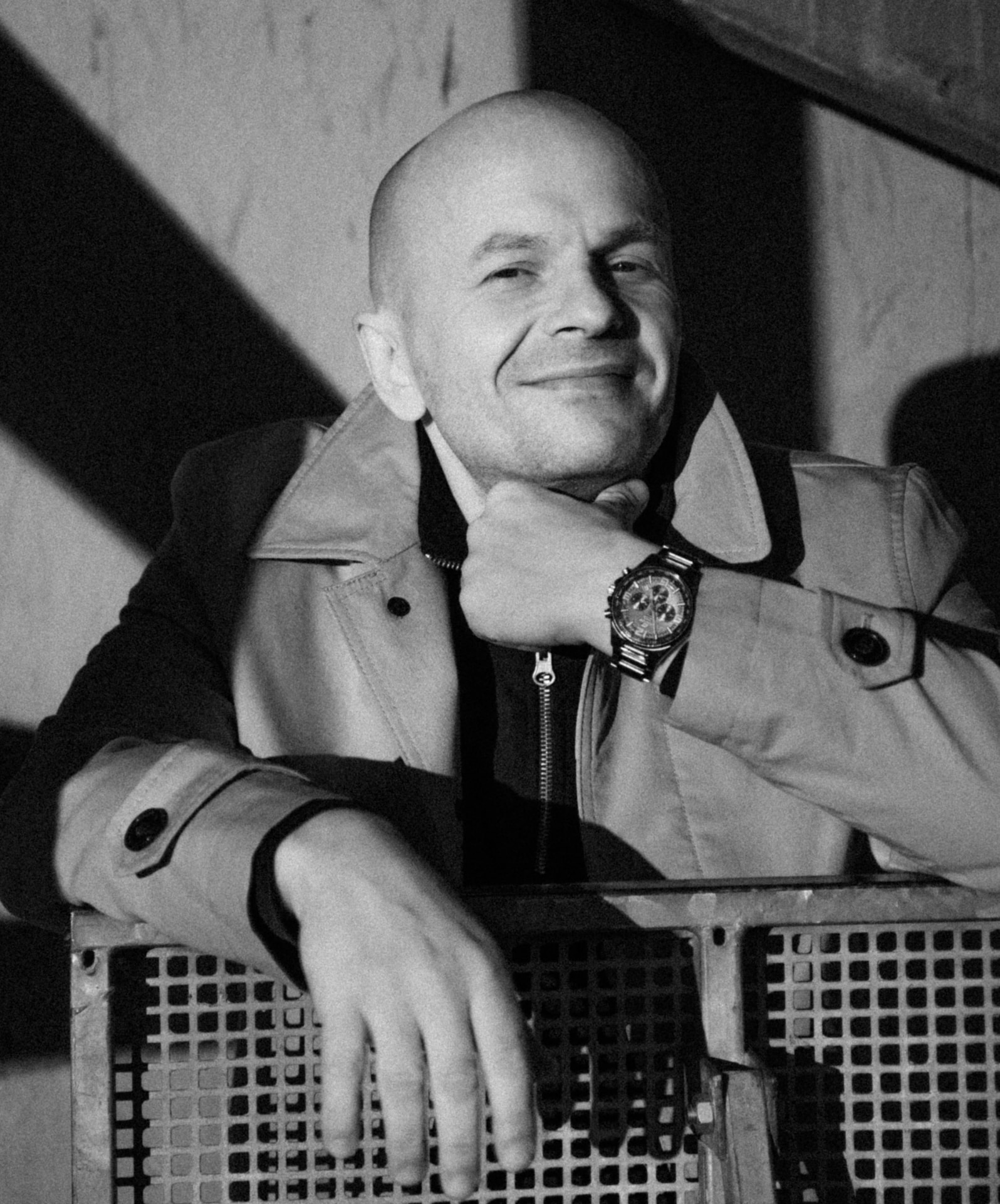 Confident bald man wearing a trench coat and wristwatch