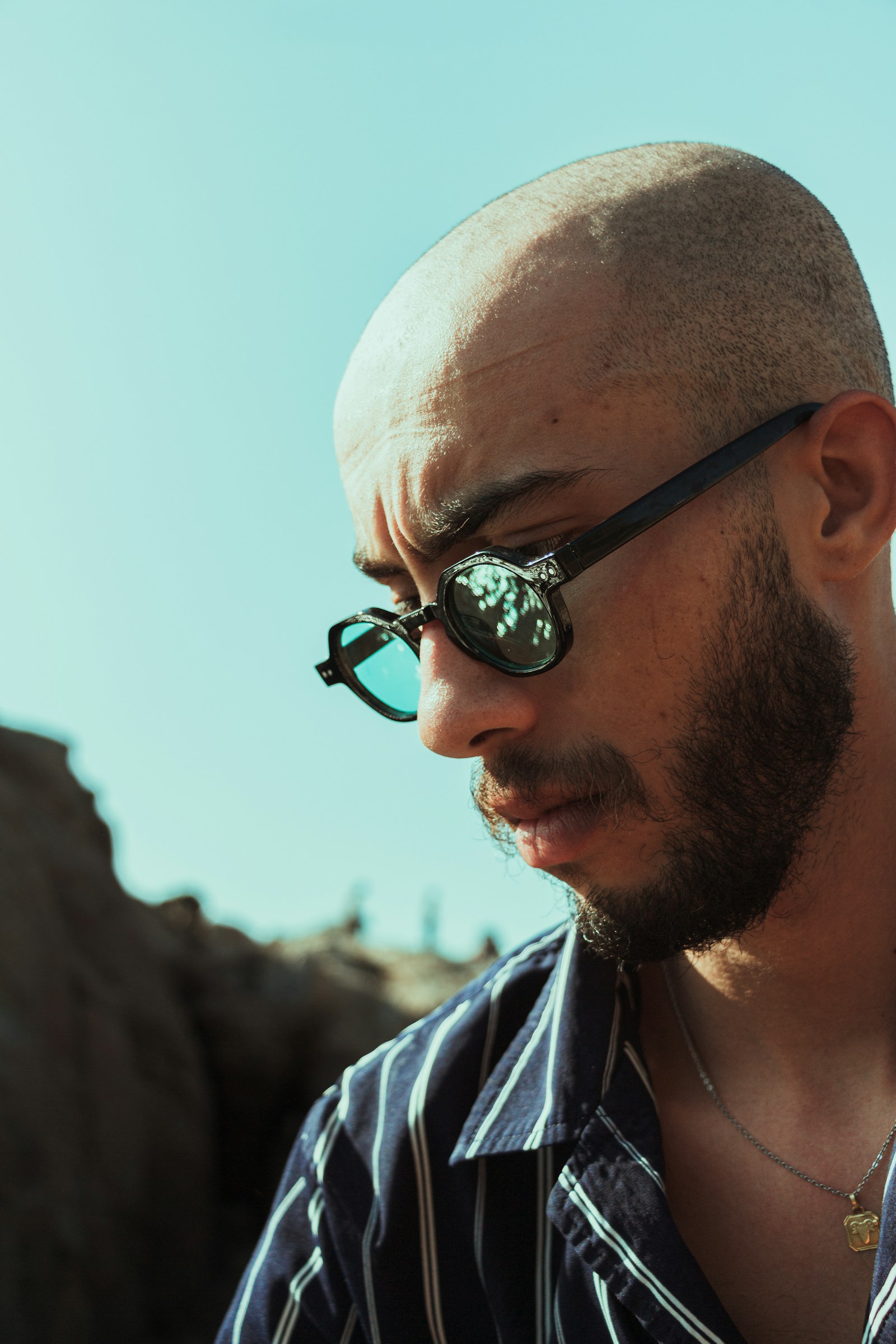 Bald man wearing sunglasses and looking down.